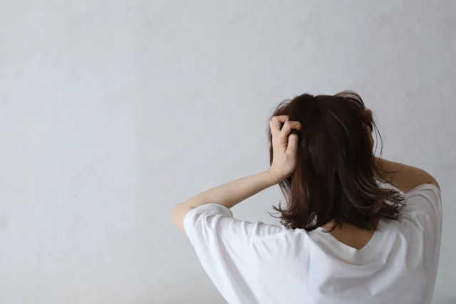 頭を抱えて悩む女性の後ろ姿