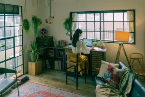 部屋で一人デスクに向かう女性の後ろ姿
