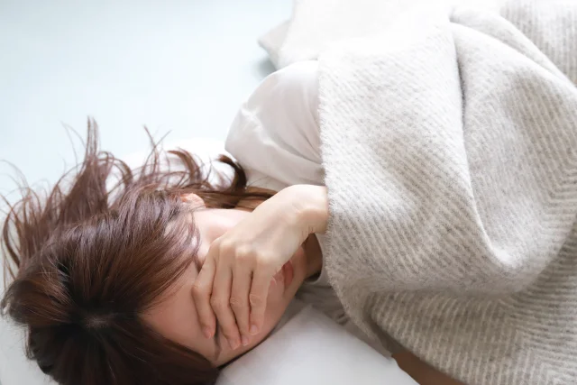 ベッドに横になる体調不良の女性