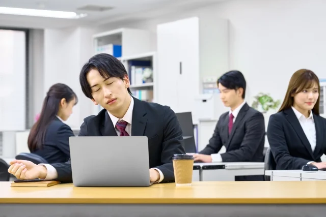 オフィスで仕事中に居眠りする男性社員