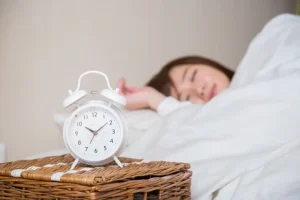 時計にピントを合わせて眠る女性