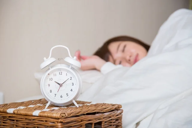 時計にピントを合わせて眠る女性