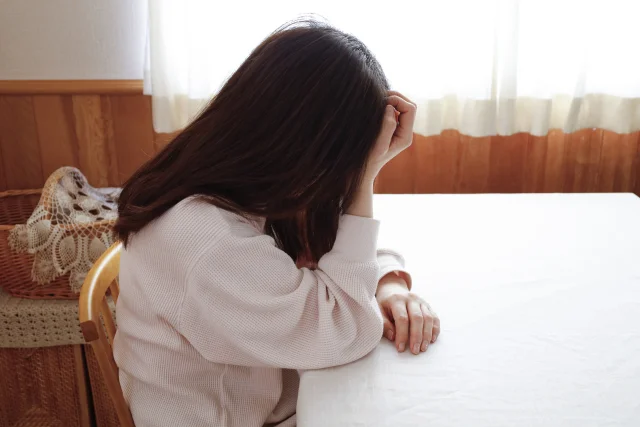 窓辺で力なくうつむく女性