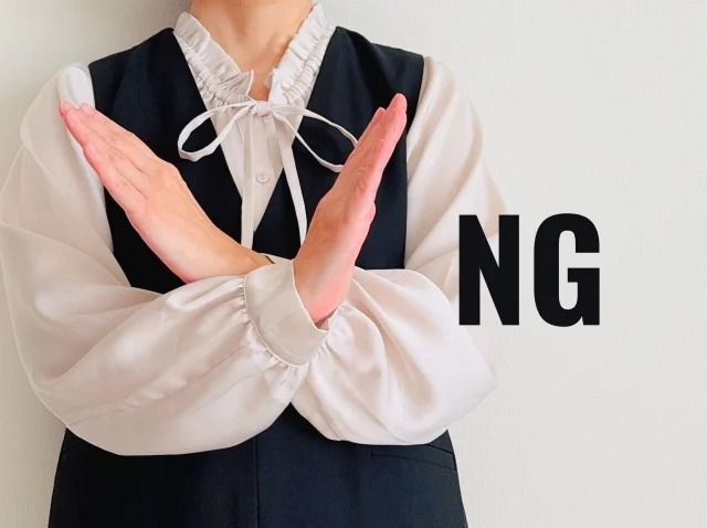 両手でNGのバツマークを作る女性
